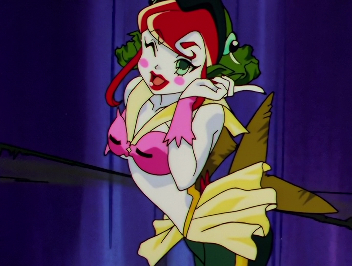 Sailor Buri, a Phage from Sailor Moon episode 173. She has pale white skin and red hair. Her top is pink, and she wears a yellow skirt as well as a yellow sailor collar. She also has a hood that looks like a fish head, and a fish-like tail. She’s wearing red lipstick and has prominent pink blush on her cheeks.